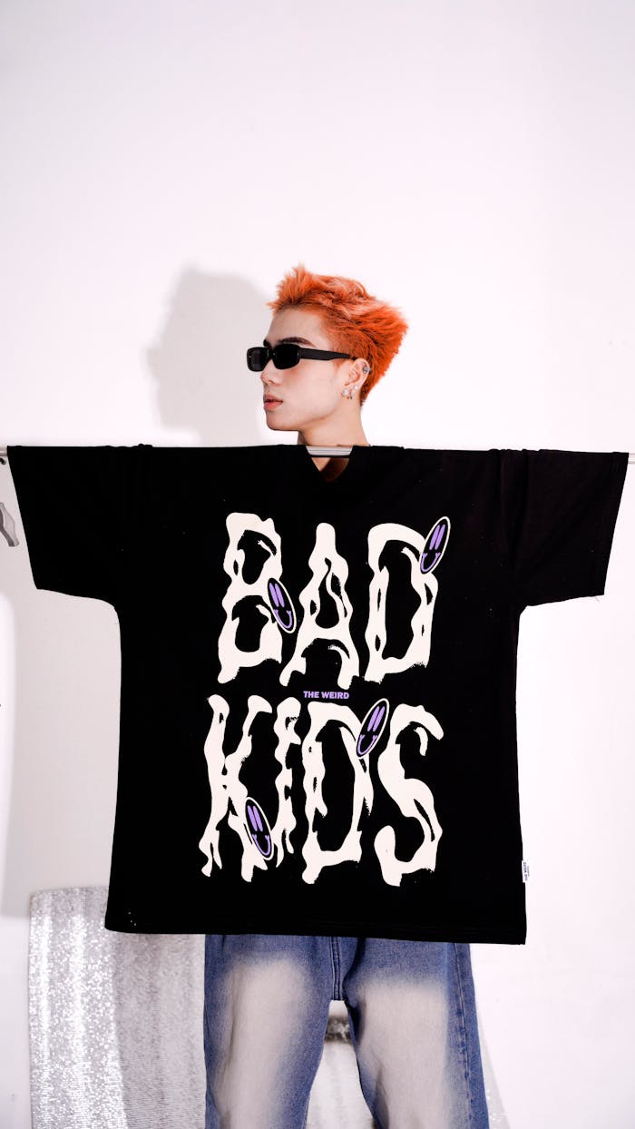 Fashion portrait of a trendy adult wearing sunglasses and oversized 'Bad Kids' t-shirt.