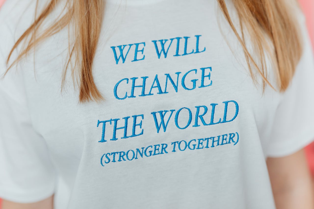 Close-up of a white t-shirt with a motivational message embroidered in blue letters.